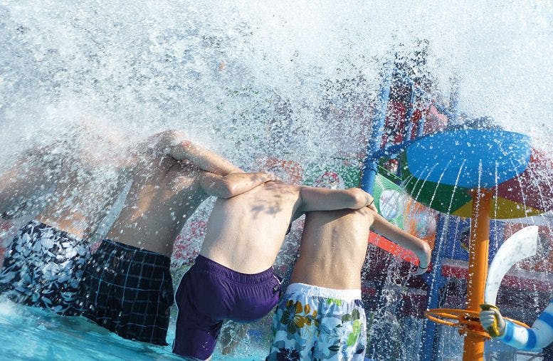 five young boys under splashing water in Waterland aquapark