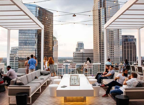 a view from the Nuvole rooftop twenty two with humans sitting on the sofas and some standing