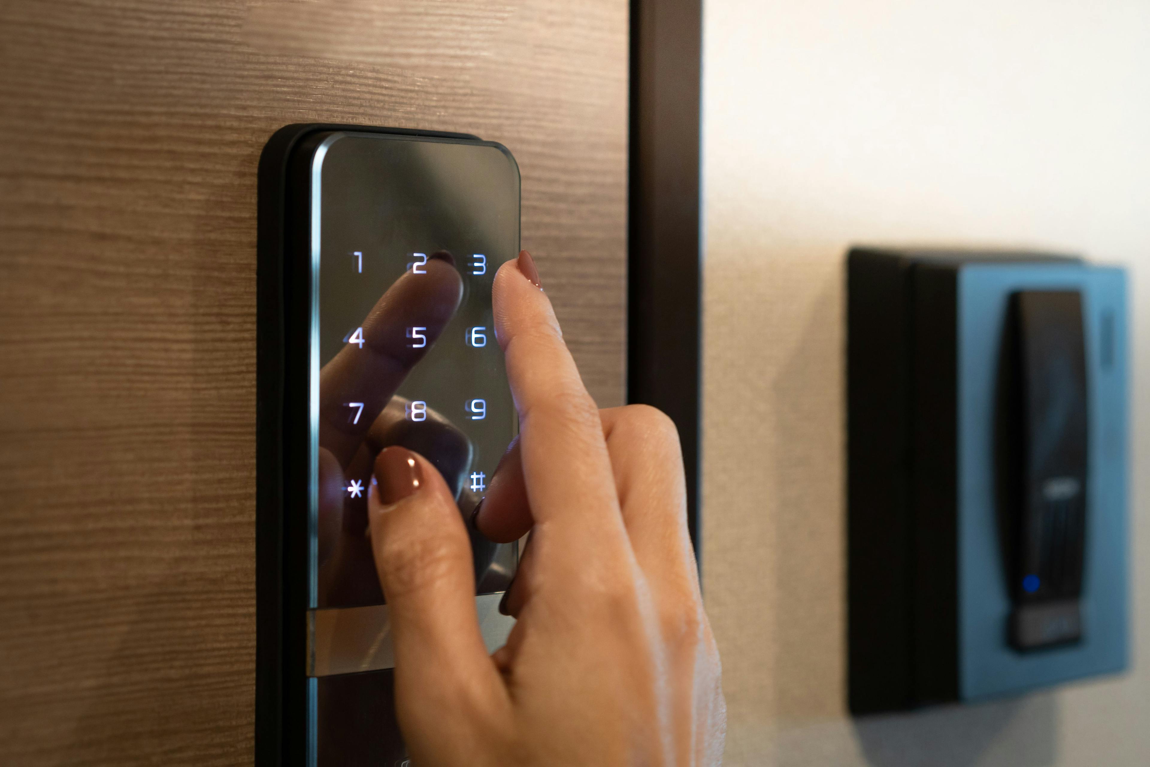 Closeup of a woman's finger entering password code on the smart digital touch screen keypad entry door lock in front of the room. 