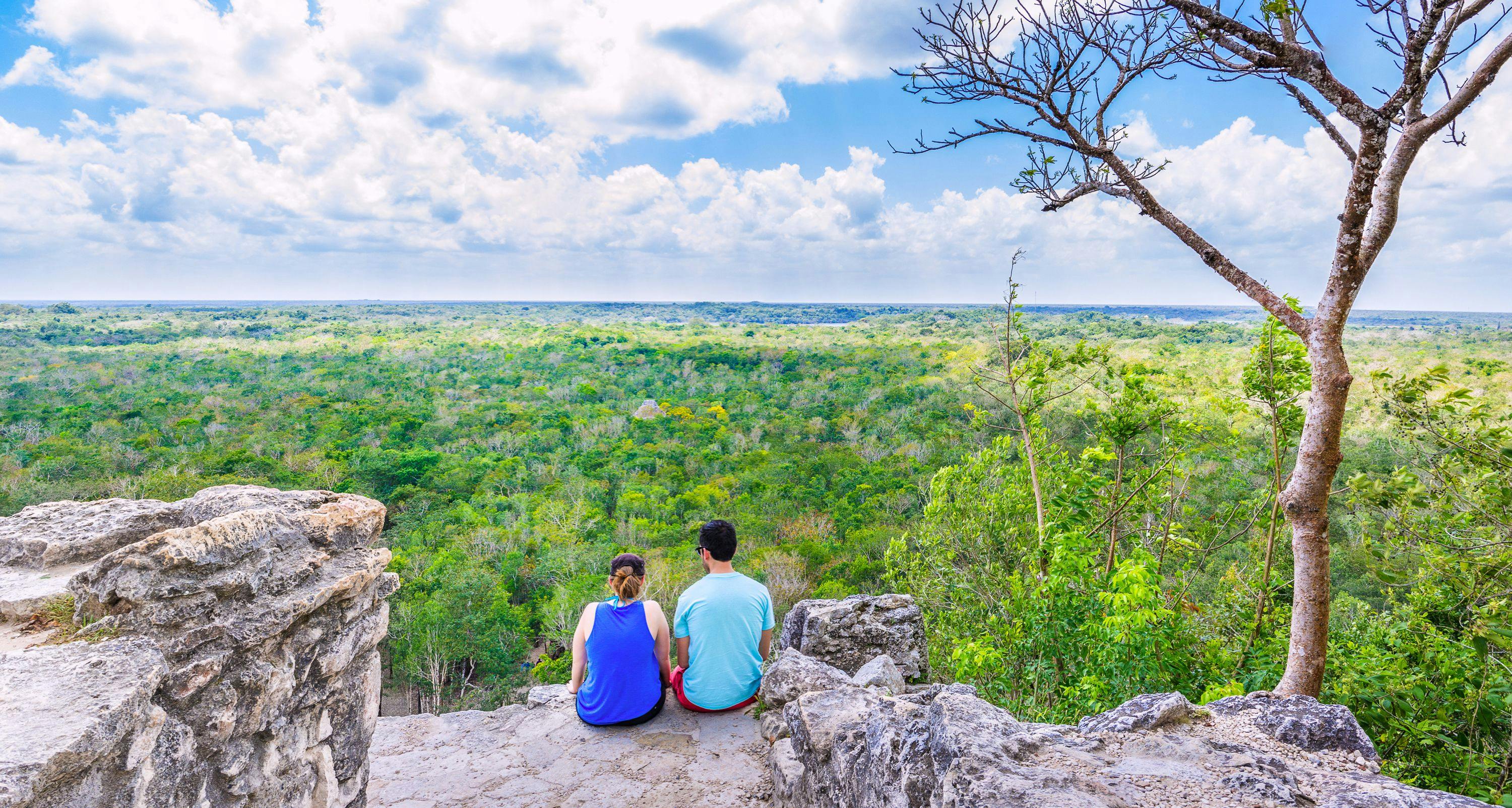 Couple on the top of Coba pyramid watching the mexican jungle
